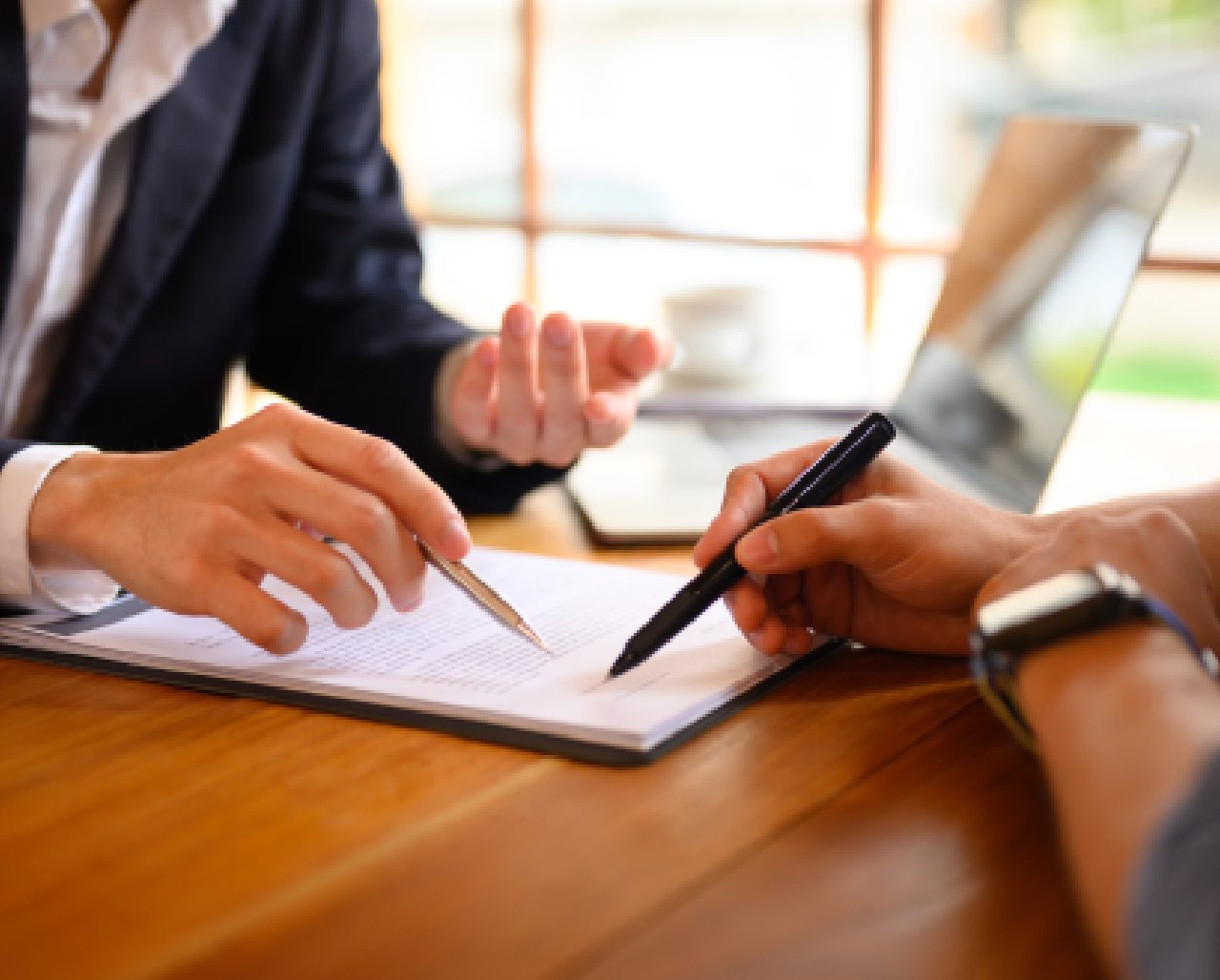 Two people are sitting at a table and one is holding a pen